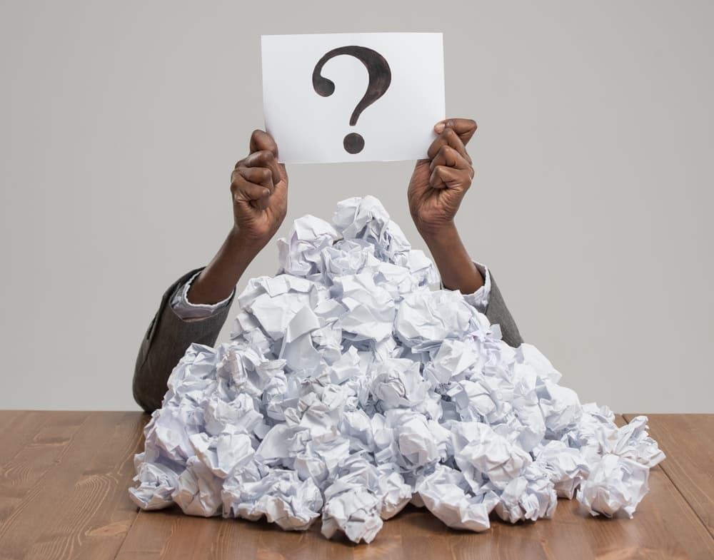 African,Business,Woman,Under,Crumpled,Pile,Of,Papers,With,Hands